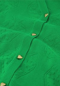 Groene gebreide cardigan met een textuurpatroon, geribbelde trim en hartvormige gouden knopen aan de voorkant.