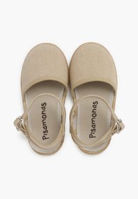 Zapatos espadrilles de lona beige con correa en el tobillo, puntera redondeada y suela de yute. El forro interior incluye el nombre de la marca "Pisamonas."