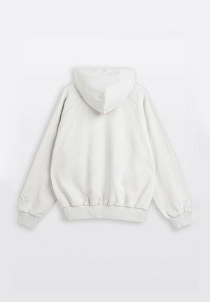 Biała bluza z kapturem pokazana od tyłu, z długimi rękawami, elastycznymi mankietami i prążkowanym ściągaczem na tle jednolitym.