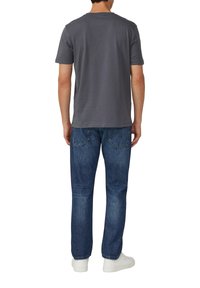 Grijze T-shirt met korte mouwen en een ronde hals, gecombineerd met blauwe denim jeans en witte sneakers, gezien vanuit de rug.