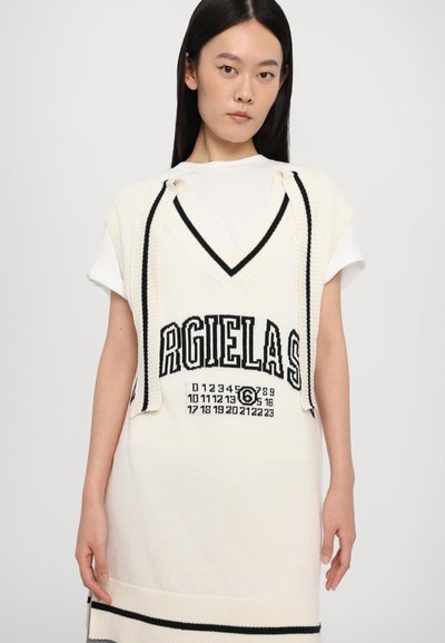 White knitted oversized vest with black trim, featuring bold lettering and grid pattern. Cap sleeves and a wide V-neck design.