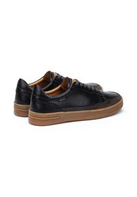 Sneakers in pelle nera con suola in gomma marrone, caratterizzati da dettagli perforati, una finitura liscia e un design tradizionale con lacci.