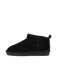Botas de tobillo de ante negro con un acabado texturizado, que presentan una punta redondeada, un perfil bajo y una suela de goma con un patrón en zigzag.