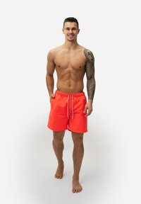 Heldere oranje zwembroek met een trekkoord in de taille, zijzakken en een textuurlogo-patch op de zoom. Lichtgewicht, boven de knie.