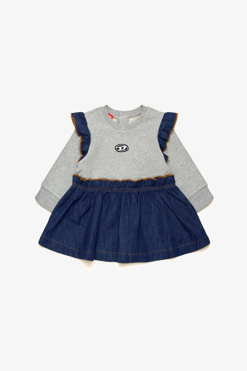 Siva dolgi rokav s krožno majico, pričvrščeno na denim krilo, ki ima nabrane rokave in okrogel logotip na prsih. Denim je enotne temno modre barve.