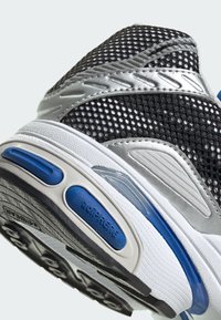 Sneaker con una toma in rete nera e dettagli in pelle argentata, imbottitura blu e suola bianca testurizzata con motivi di trazione neri.