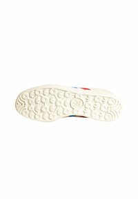 Fehér sneaker talp, amely texturált mintázattal rendelkezik, körkörös és hullámos minták találhatók rajta; az oldalain piros és kék díszítések találhatók.
