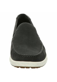 Scarpe slip-on nere con tomaia testurizzata e perforazioni, suola bianca a contrasto e design con punta rotonda.