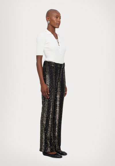 White ribbed polo shirt with collar, paired with black, sequined wide-leg pants featuring vertical stripes and black flats.