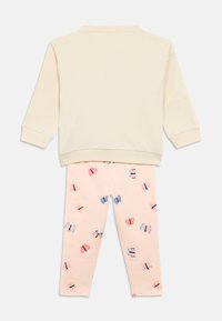 Light beige sweatshirt with a round neckline and long sleeves paired with pink leggings featuring a butterfly print in various colors.
