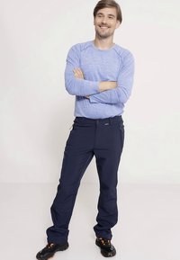 Zila garām piedurknēm krekls ar brīvu piegulumu, kopā ar tumši ziliem āra biksēm ar sānu kabatām un gludu faktūru. Melnas kurpes ar oranžām detaļām.