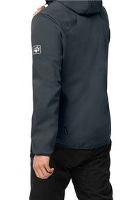 Mörkgrå vattentät jacka med huva, försedda med en logotypapplikation på vänstra ärmen, slät textur och en strömlinjeformad design.