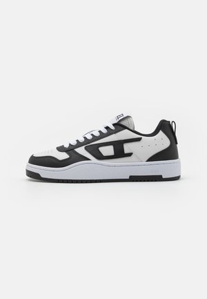 White and black sneaker with a textured leather upper, padded collar, round toe, and contrasting rubber sole. Includes white laces and logo detail.