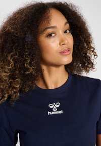 Marineblauwe t-shirt van katoen, met een ronde halslijn en korte mouwen. Inclusief een wit logo op de borst. Gladde textuur.