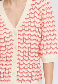 Cardigan en tricot avec un col en V, de couleur crème avec un motif ondulé corail, des manches courtes bouffantes et de grands boutons à l'avant. Design texturé en maille ouverte.