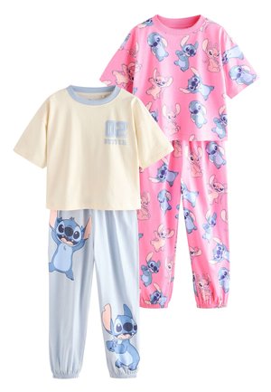Zwei Mädchen tragen passende Schlafanzüge. Das erste Set ist rosa mit Comicfiguren. Das zweite Set ist hellblau mit einem Muster auf der Hose.