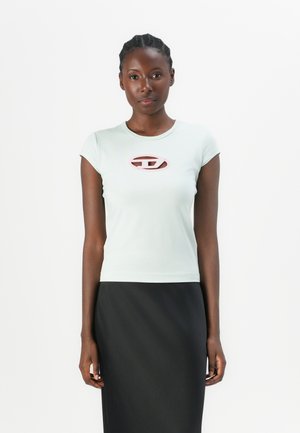 Light blue short-sleeve fitted t-shirt with a pink oval logo at the chest, worn with a black skirt. Smooth fabric and minimal design.