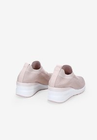 Sneakers a maglia rosa chiaro con tomaia in rete testurizzata, lacci elastici senza nodo e suola a piattaforma bianca. Dettagli posteriori lisci e linguetta sul tallone.