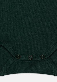 Bodysuit côtelé vert foncé avec des boutons-pression au bas, au toucher doux et à la coupe ajustée.