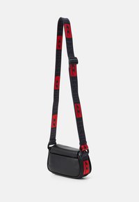Borsa a tracolla in pelle nera con forma strutturata; presenta una lunga tracolla regolabile con dettagli rossi e testo del logo.