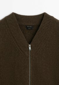 Pull en laine marron côtelé avec col en V et fermeture éclair argentée, montrant le col et l’étiquette de la marque « Massimo Dutti ».
