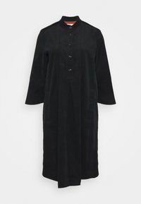 Cappotto lungo nero con collo alla mandarina, chiusura frontale con bottoni, due tasche laterali e un tessuto liscio e testurizzato.