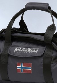 Gray fabric duffel bag with black straps, featuring a front pocket and a small Norwegian flag patch. Brand logo visible on top.