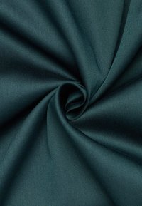 Tessuto intrecciato di colore teal, texture liscia, con una leggera lucentezza; raccolto strettamente in una formazione a spirale, che mette in mostra linee diagonali e creste.