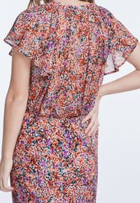 Blumendruckkleid in Orange-, Lila- und Grüntönen; leichtes, durchsichtiges Material, flatternde Ärmel, geraffter Ausschnitt, taillierter Schnitt.