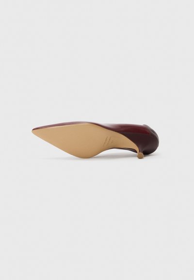 Burgundin väriset korkeat korkokengät, joissa on terävä kärki ja kapea korko. Suklainen nahkamateriaali, jossa on beige pohja ja pieni metallinen yksityiskohta kannassa.