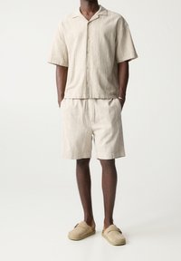 Linnen overhemd met korte mouwen in beige met lichte strepen, gecombineerd met bijpassende beige shorts en tan instappers.