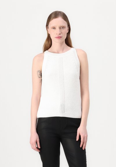 Haut sans manches en tricot blanc avec un motif texturé et un col rond, associé à un pantalon noir. Design simple et décontracté sans embellissements.
