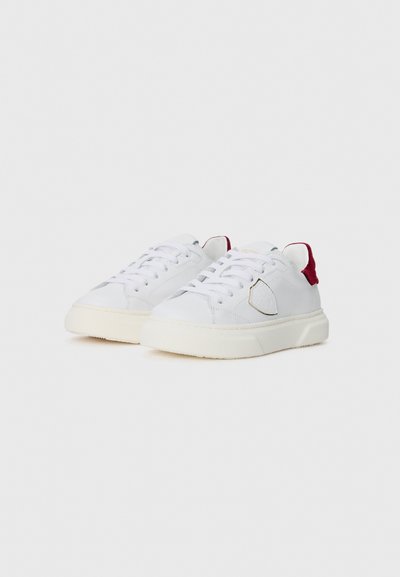 Weiße Leder-Sneaker mit einer strukturierten roten Ferseneinlage, flachen Schnürsenkeln und einer leichten Plateau-Sohle. Verfügt über einen dekorativen seitlichen Patch.