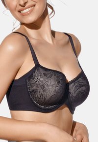  sujetador negro con un diseño elegante, adornado con un patrón ondulado texturizado. Presenta tirantes ajustables y un borde de encaje decorativo a lo largo de los bordes.