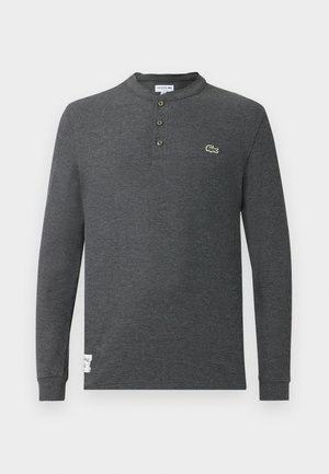 Gray long-sleeve henley shirt with a ribbed texture, featuring three buttons at the collar and a green crocodile logo on the left chest.