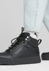 Czarne półbuty sportowe z gładkiej skóry i teksturowanymi akcentami. Posiadają czarne sznurowadła, gumową podeszwę oraz logo po boku.