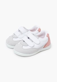 Zapatilla gris y blanca con acentos rosas, con una textura de ante, forma redonda y dos correas de Velcro para un fácil ajuste.