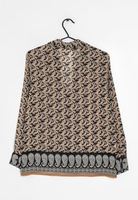 Blouse noire avec un motif cachemire en orange et crème. Elle a un col rond, des manches longues et un ourlet inférieur détaillé.