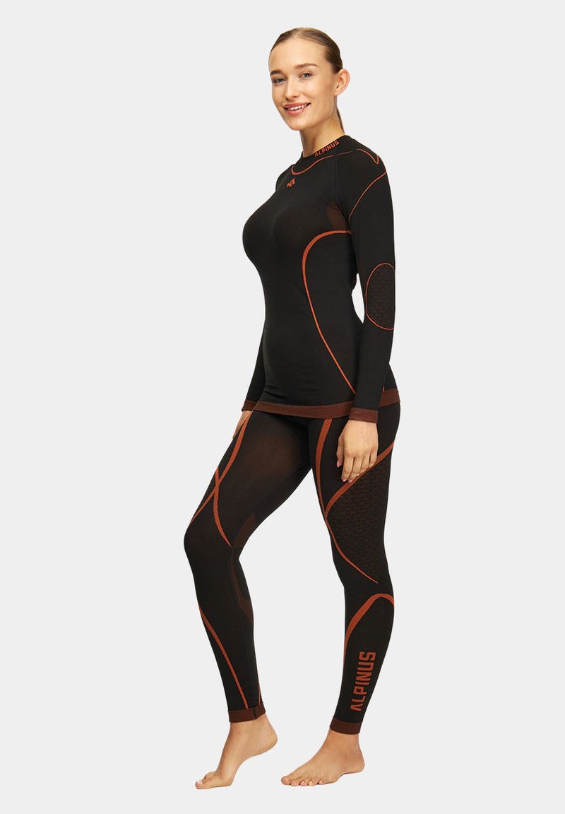 Czarny zestaw odzieży sportowej z długimi rękawami i legginsami, z pomarańczowymi akcentami, teksturowanym materiałem i dopasowanym krojem.
