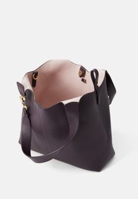 Purple leather tote bag with a textured finish, scalloped top edge, light interior, and gold hardware accents. Adjustable shoulder strap included.