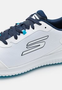 White athletic shoe with mesh upper, navy blue laces, and logo detail. Features textured sole with contrasting aqua accents.