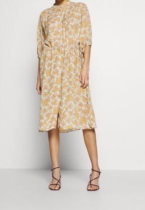 Blommönstrad midiklänning i lätt tyg, med hög halsringning, åtdraget midja och korta ärmar. Förstärkt med sidokjolar.