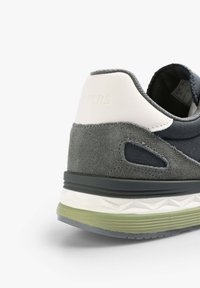 Sneaker grigio in suede e tessuto con un accento bianco sul tallone, caratterizzato da una suola testurizzata. Include ritagli e un design leggero.