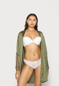 Olijfgroene satijnen ochtendjas met kanten accenten, gecombineerd met een witte beha met kant en bijpassende slip. Gladde texturen en delicate details.