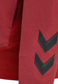 Rode sweatshirt met een gestructureerde stof, een pocketdetail en een zwart chevronpatroon op de mouw. Glad en ademend materiaal.