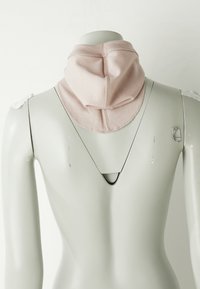 Mannequin-Rücken mit einem hellrosa Stoffhalswärmer oder Snood, der um den Hals gelegt ist, vor einem weißen Hintergrund.