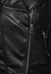 Giubbotto in pelle nera con cerniere, finitura testurizzata, design frontale asimmetrico e numerose tasche con cerniera.