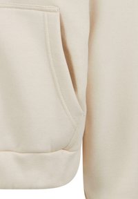 Light beige sweatshirt featuring a kangaroo pocket and ribbed cuffs. Made of soft, textured fabric with a relaxed fit.