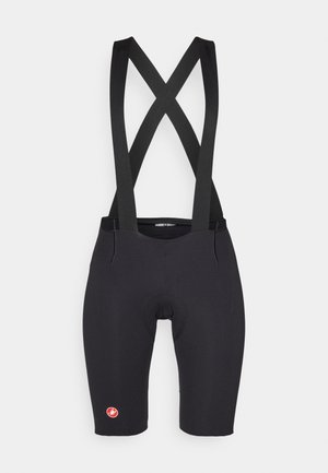 Calções de ciclismo pretos com suspensórios cruzados, feitos de tecido elástico, apresentando um assento almofadado e um pequeno logo vermelho na perna.