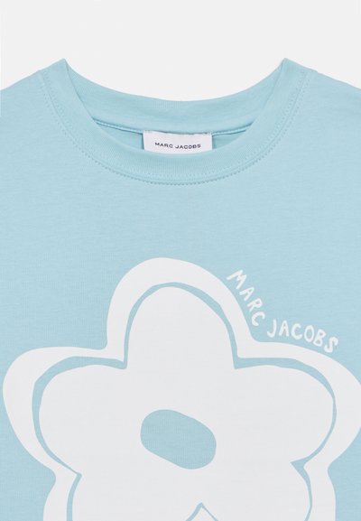 Φωτεινό γαλάζιο βαμβακερό T-shirt με μεγάλο λευκό γραφικό λουλούδι και το κείμενο «MARC JACOBS» σε καμπυλω τό σχέδιο. Λείο ύφασμα, στρογγυλή λαιμόκοψη.